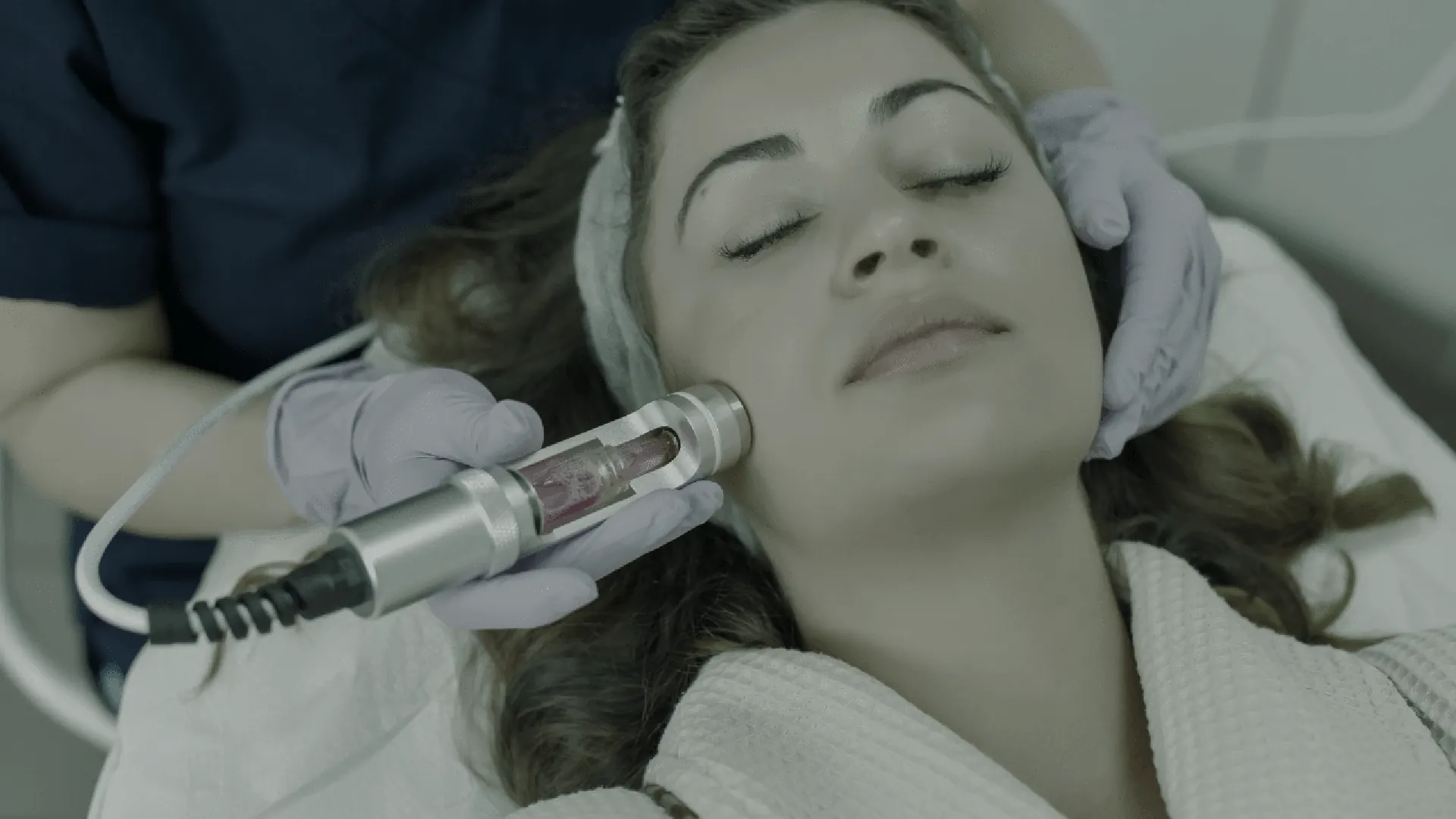 Client receiving a facial exosome treatment with a cooling device
