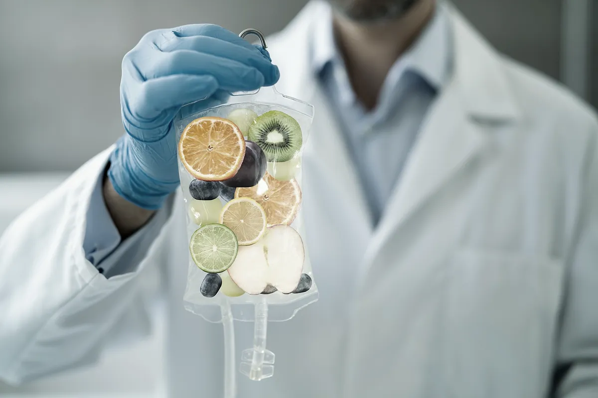 Practitioner holding an IV drip bag with fresh fruit inside, symbolising nutrient infusion