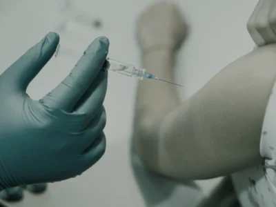 Gloved hands preparing a vitamin injection in a syringe