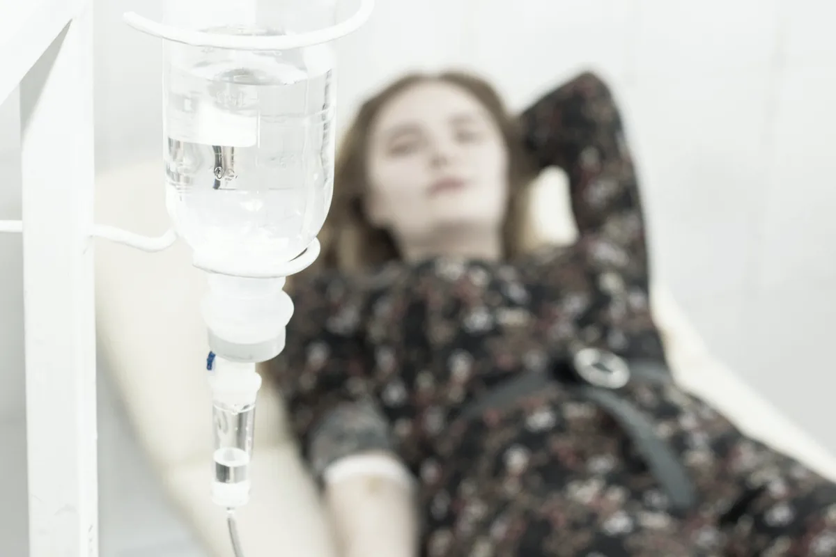 Client resting in a white treatment chair during an IV infusion