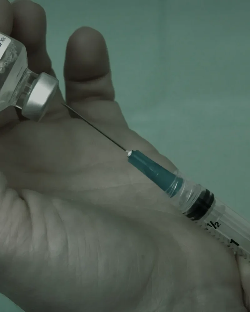 Peptide vial and insulin syringe on a white surface